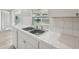 Close-up of the stainless steel double sink and white tile countertops by the kitchen window at 2079 Pellam Blvd, Port Charlotte, FL 33948