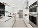 Modern white kitchen featuring stainless steel appliances, island seating, and an open layout at 301 Quay Commons # 1809, Sarasota, FL 34236