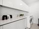 Modern laundry room featuring white cabinetry, sleek countertops, sink, and front load washer and dryer at 301 Quay Commons # 1809, Sarasota, FL 34236