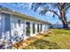 Wide view of backyard with patio doors, mature trees and a green lawn at 3446 Monica Pkwy, Sarasota, FL 34235