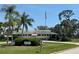 Community clubhouse with an American flag, palm trees, and well-maintained landscaping at 3739 Collins St # 701, Sarasota, FL 34232