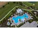 Aerial view of a large outdoor pool area with lounge chairs and umbrellas, adjacent to a golf course at 3860 Santa Caterina Blvd, Bradenton, FL 34211