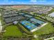 Aerial shot of multiple tennis courts in a community with surrounding houses and green landscape at 3860 Santa Caterina Blvd, Bradenton, FL 34211