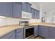 Modern kitchen showcasing stainless steel appliances, blue cabinets, light countertops, and a white microwave at 4244 Reflections Pkwy, Sarasota, FL 34233