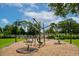 A playground with unique swing features in the park on a wood chip surface and benches and green grass surroundings at 4244 Reflections Pkwy, Sarasota, FL 34233