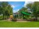 A colorful playground with slides, climbing structures and shade surrounded by mature trees and green grass at 4244 Reflections Pkwy, Sarasota, FL 34233