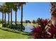 Beautiful community pond surrounded by greenery, features a fountain and tropical plants at 4244 Reflections Pkwy, Sarasota, FL 34233