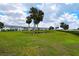 Beautiful lawn with mature palms trees, pond and a waterfront condo in the background at 4722 Independence Dr, Bradenton, FL 34210