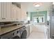 Well-lit laundry room area featuring sleek stainless steel washer/dryer, granite counters, white cabinets and ample storage at 4722 Independence Dr, Bradenton, FL 34210