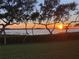 Stunning sunset view over the water, framed by silhouetted trees and green lawn at 4722 Independence Dr, Bradenton, FL 34210