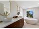 Bright bathroom featuring dual vessel sinks, stylish gold fixtures, textured accent wall, and a modern soaking tub at 505 65Th St, Holmes Beach, FL 34217