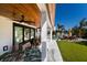 Covered patio with unique wooden furniture and lush green lawn leading to a pool and lounge area at 505 65Th St, Holmes Beach, FL 34217