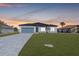 New home exterior at dusk, featuring light-colored siding and gray paver driveway at 514 Santiguay St, Punta Gorda, FL 33983