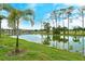 Scenic pond view showcasing clear reflections, mature palm trees, and lush green landscaping at 5276 Mahogany Run Ave, Sarasota, FL 34241