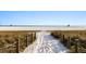 Sandy path leads to a pristine beach with lifeguard towers in the distance under a clear sky at 5630 Saint Louis Ave, Sarasota, FL 34233