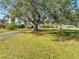 A view of home showcasing the large front yard and mature shade trees at 5630 Saint Louis Ave, Sarasota, FL 34233