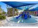 Colorful playground with slides and play structures shaded by blue canopies, near a sandy area at 5630 Saint Louis Ave, Sarasota, FL 34233