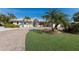 Charming single-story home featuring brick driveway, lush lawn, and mature palm trees at 627 Dundee Ln, Holmes Beach, FL 34217