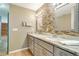 Bathroom vanity with double sinks, granite counters, mosaic backsplash, and shaker cabinets at 6521 121 St E Ave, Parrish, FL 34219