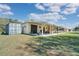 Exterior view of tan house featuring an outdoor patio, shipping container, and green grass at 6521 121 St E Ave, Parrish, FL 34219