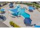 Aerial shot of a community pool area with unique design, shaded seating, and lush landscaping around the perimeter at 7103 Westhill Ct, Lakewood Ranch, FL 34202