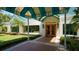 A welcoming entrance to The Varsity Club, featuring a blue and tan awning, glass windows, and well-maintained landscaping at 7327 Kensington Ct, University Park, FL 34201