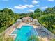 Aerial view of the community pool and jacuzzi with a building, surrounded by tropical landscaping at 7327 Kensington Ct, University Park, FL 34201