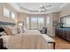 Inviting main bedroom featuring tray ceiling, ceiling fan and hardwood floors with natural light from multiple windows at 7327 Kensington Ct, University Park, FL 34201