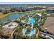 An aerial view of a community pool area with a water park, lake, and residential homes in the background at 12410 Osorio Ct # 201, Sarasota, FL 34238