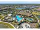 An aerial view of a luxurious community pool, clubhouse, tennis courts, and a lake with homes in the background at 12410 Osorio Ct # 201, Sarasota, FL 34238