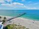 Scenic aerial view showcases the pier extending over clear blue water and sandy shoreline at 12675 Richezza Dr, Venice, FL 34293