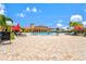 Expansive pool area with comfortable seating, red umbrellas, and a nearby building at 12675 Richezza Dr, Venice, FL 34293