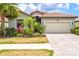 Inviting single-Gathering home with lush tropical landscaping, a clay tile roof, and a two-car garage at 12675 Richezza Dr, Venice, FL 34293