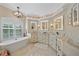 Bright bathroom with modern sinks, chandelier, and a free standing tub with shuttered window at 2023 Micanopy Trl, Nokomis, FL 34275