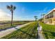 Serene exterior view of beachside condos with manicured lawn, palm trees, and an ocean view at 2089 Gulf Of Mexico Dr # G1-205, Longboat Key, FL 34228