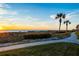 Scenic walkway lined with palm trees and greenery, leading to the beach at sunset at 2089 Gulf Of Mexico Dr # G1-205, Longboat Key, FL 34228