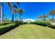 A manicured lawn features a sign for 'The Beach Club' under a bright blue sky and lush palm trees at 272 Saint Lucia Dr # 101, Bradenton, FL 34209