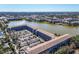 Aerial view of the condo building, lake, parking lot, surrounding landscape and other buildings in the distance at 3050 Lake Bayshore Dr # O-108, Bradenton, FL 34205