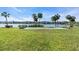 Backyard with a shuffleboard court, lake, and lawn and condo building in the background at 3050 Lake Bayshore Dr # O-108, Bradenton, FL 34205