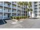 Multi-story condo building with gray exterior, white railings, tropical landscaping, and ample parking at 3050 Lake Bayshore Dr # O-108, Bradenton, FL 34205