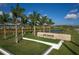 Entrance to Esplanade at Azario Lakewood Ranch with lush green grass, landscaping, and palm trees at 3105 Formia Ct, Bradenton, FL 34211