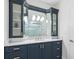 Bathroom with navy blue vanity, marble countertop, and a large mirror featuring storage cabinets on either side at 3759 Beneva Oaks Blvd, Sarasota, FL 34238