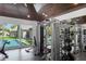 Bright home gym with an exposed-beam ceiling, large windows, and modern exercise equipment overlooking the pool at 3759 Beneva Oaks Blvd, Sarasota, FL 34238