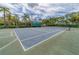 Outdoor tennis court showcasing a well-maintained court surface and net amidst lush surroundings at 4969 Creekside Trl, Sarasota, FL 34243