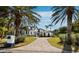 An exterior view of a grand home with a private front yard, beautiful palm trees and a brick paved driveway at 500 Harbor Point Rd, Longboat Key, FL 34228