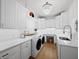 Bright laundry room with white cabinets, a sink, and modern washer and dryer units at 500 Harbor Point Rd, Longboat Key, FL 34228