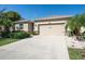 Beautiful beige home featuring a two-car garage, manicured landscaping, and decorative stone accents at 5718 Broad River Run, Ellenton, FL 34222