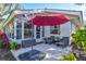 Outdoor patio seating area with comfortable chairs under a vibrant red umbrella at 5718 Garden Lakes Palm, Bradenton, FL 34203