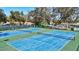 Bright blue tennis courts offering ample recreational opportunities, surrounded by mature trees at 5718 Garden Lakes Palm, Bradenton, FL 34203