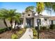 Home's entry featuring a stone facade, turquoise front door, and lush tropical landscaping at 6373 Royal Tern Cir, Bradenton, FL 34202